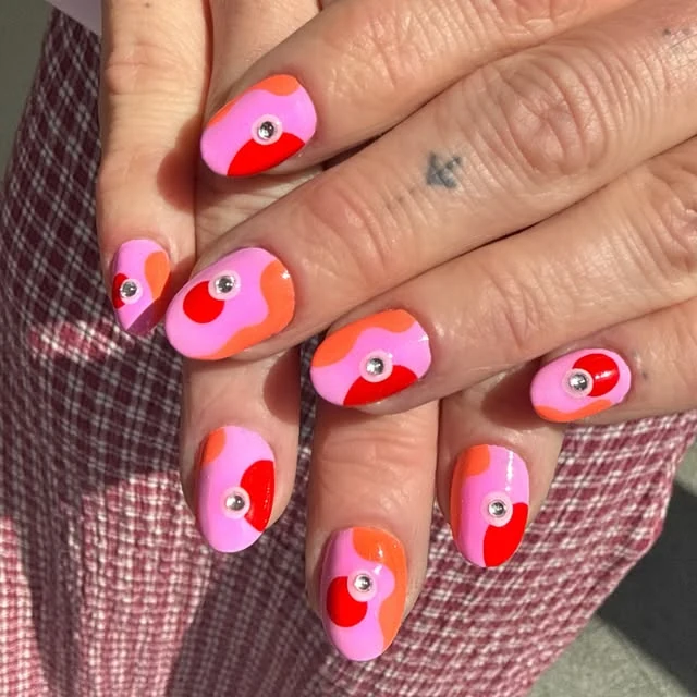 Pink and orange nail art with playful eye motifs